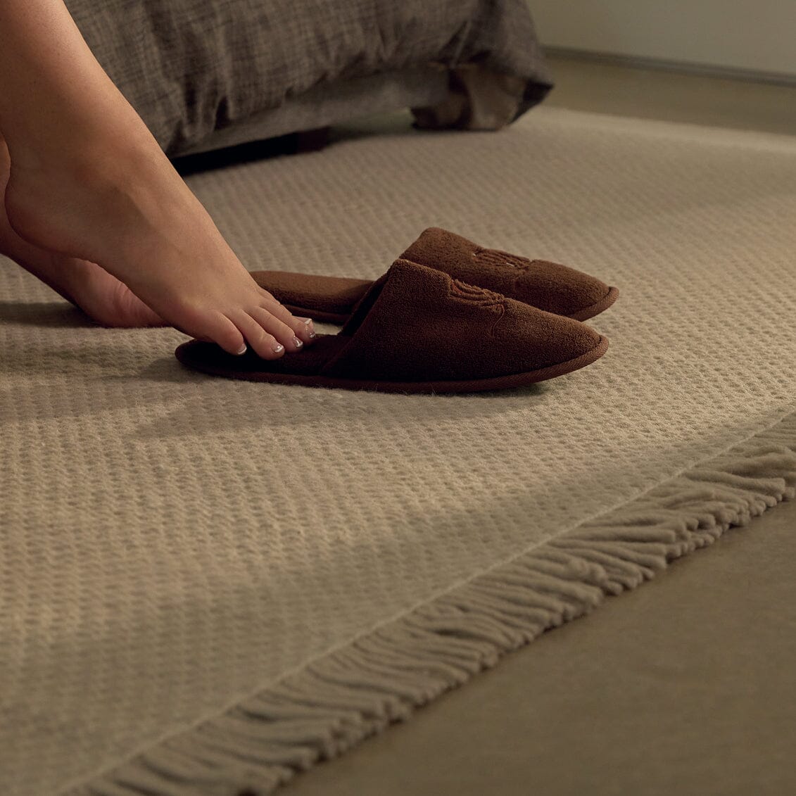 Brown slippers on a textured rug with a blurred dog in the background #foggray